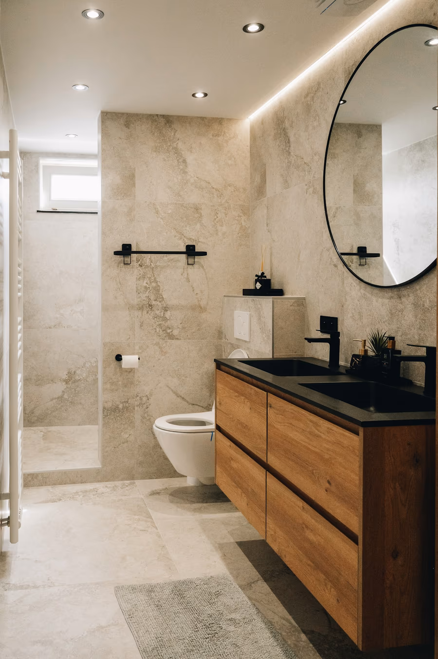 Bathroom with large-format stone-look wall tile, a floating wood vanity and a walk-in shower behind a glass panel